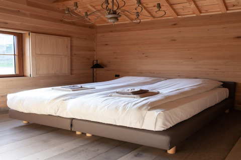 Cozy bedroom with double bed, wood paneling, and a window at Lodge Happiness in Belgium.