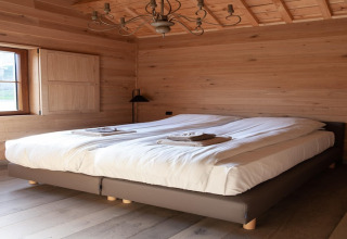 Cozy bedroom with double bed, wood paneling, and a window at Lodge Happiness in Belgium.