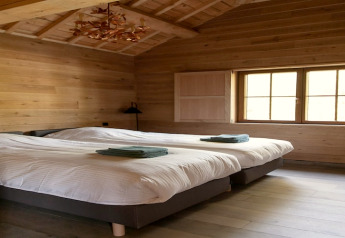 Stanza del lodge «Happiness» in Belgio con due letti singoli, pareti in legno e luce naturale.