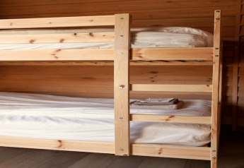 Foto di un letto a castello in legno con lenzuola pulite in un lodge chiamato «Happiness» in Belgio.