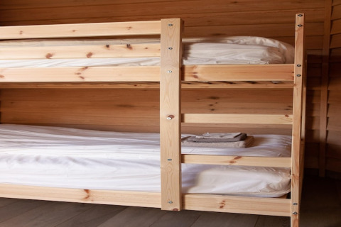 A photo of a wooden bunk bed with clean bedding at a lodge named «Happiness» in Belgium.