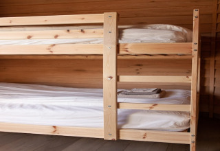 A photo of a wooden bunk bed with clean bedding at a lodge named «Happiness» in Belgium.
