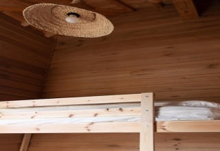 Wooden bunk bed and woven lampshade in the interior of the 'Happiness' lodge in Belgium.