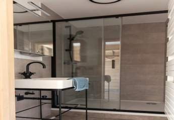 Bagno moderno al lodge 'Happiness' in Belgio con rubinetto nero, lavabo e box doccia in vetro.