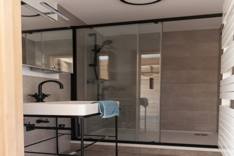 Modern bathroom at lodge 'Happiness' in Belgium featuring a black faucet, sink, and glass shower.