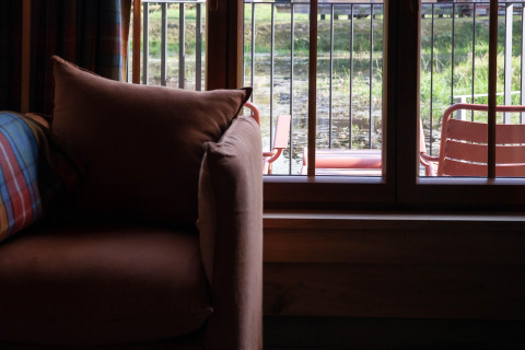 View from a cozy sofa by the window at Lodge ‘Happiness’ in Belgium, showing terrace and greenery.