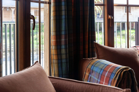 View from the living room at lodge “Happiness” in Belgium, with plaid blanket and green scenery outside.