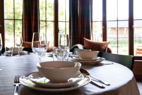 Table set with bowls and glassware in a Belgian lodge named 'Happiness' with bright windows in view.