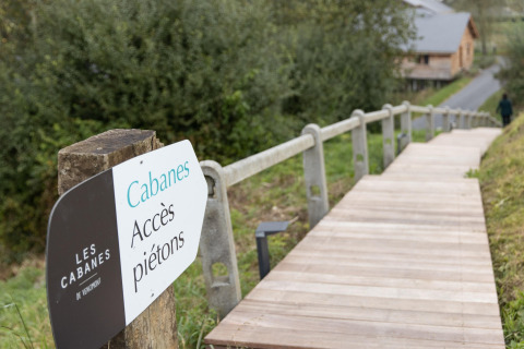 Pedestrian access sign and wooden walkway at Les Cabanes de Vencimont 'Happiness' lodge in Belgium.