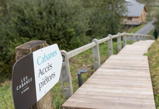 Pedestrian access sign and wooden walkway at Les Cabanes de Vencimont 'Happiness' lodge in Belgium.