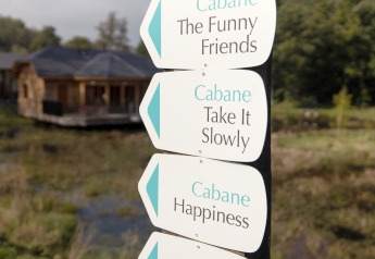 Cartelli con scritte 'Cabane The Funny Friends', 'Take It Slowly' e 'Happiness' vicino a un lodge in Belgio.