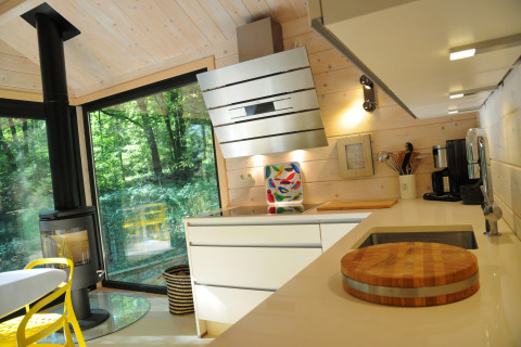 Moderne keuken in chalet ‘Drôles d'écureuil’ in België met veel hout, haard en grote ramen.