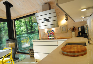 Moderne keuken in chalet ‘Drôles d'écureuil’ in België met veel hout, haard en grote ramen.