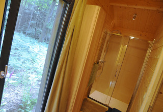 Badkamer met glazen douche en groot raam met uitzicht op bos, in chalet Droles d'écureuil in België.