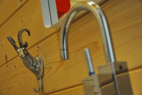 Close-up van een decoratieve metalen dierenhaak op houten wand in chalet 'Droles d'écureuil' in België.