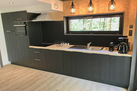 Modern kitchen at Village de Vacances Oignies 5 in Belgium with wood countertop and hanging lights.