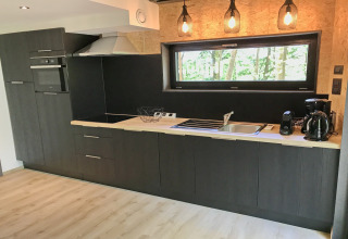 Modern kitchen at Village de Vacances Oignies 5 in Belgium with wood countertop and hanging lights.