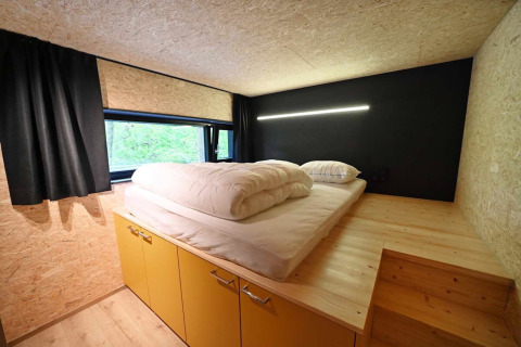Cozy bedroom with a large bed, yellow cabinets, and window at Village de Vacances Oignies 5 in Belgium.