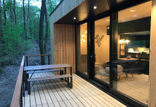Wooden terrace with picnic bench at a modern lodge in Village de Vacances Oignies 5, Belgium, in the woods.