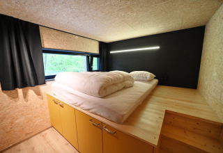Modern bedroom at lodge Village de Vacances Oignies 5 in Belgium, with double bed, steps, and a window.