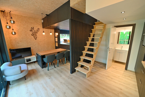 Modern lodge interior at Village de Vacances Oignies 5, Belgium, featuring wood stairs and dining area.