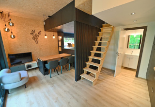 Modern lodge interior at Village de Vacances Oignies 5, Belgium, featuring wood stairs and dining area.