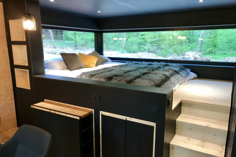 Modern bedroom with large windows offering forest views at Village de Vacances Oignies 5 in Belgium.