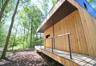 Modern wooden lodge with small terrace in the woods at Village de Vacances Oignies 5, Belgium, sunny day.