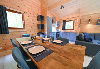 Zona pranzo e soggiorno in uno chalet di legno con cucina moderna a Village de Vacances Oignies 6, Belgio.
