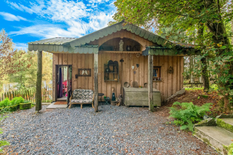 Rustic wooden yurt named La Pause Insolite in Belgium, set amidst lush greenery and tranquil surroundings.