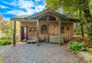 Rustic wooden yurt named La Pause Insolite in Belgium, set amidst lush greenery and tranquil surroundings.