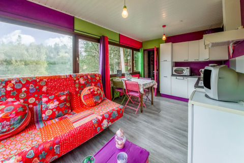 Colorful living room and kitchen in a yurt at La Pause Insolite, Belgium, decorated with red and purple.