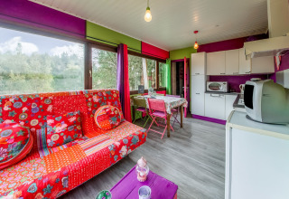 Colorful living room and kitchen in a yurt at La Pause Insolite, Belgium, decorated with red and purple.