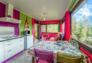 Colorful yurt interior at La Pause Insolite in Belgium featuring bright decor and large windows with nature views.