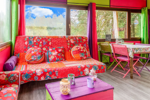 Colorful interior of yurt 'La Pause Insolite' in Belgium with patterned sofa and vibrant curtains.