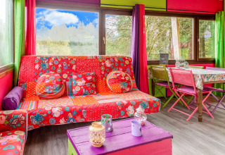 Colorful interior of yurt 'La Pause Insolite' in Belgium with patterned sofa and vibrant curtains.