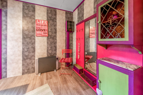 Colorful yurt interior with striped walls, a large mirror, bright furniture and sign, La Pause Insolite, Belgium.
