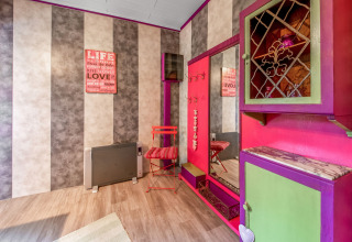 Colorful yurt interior with striped walls, a large mirror, bright furniture and sign, La Pause Insolite, Belgium.