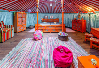 Colorful yurt interior with Mongolian decor, cozy furnishings and bed at La Pause Insolite in Belgium.