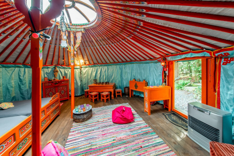 Colorful yurt interior with traditional furniture at La Pause Insolite in Belgium, featuring cozy decor.