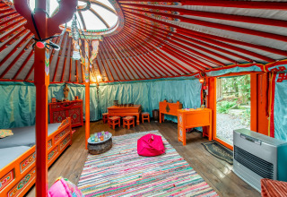 Colorful yurt interior with traditional furniture at La Pause Insolite in Belgium, featuring cozy decor.