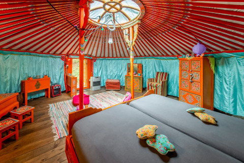 Colorful interior of a traditional Mongolian yurt called La Pause Insolite in Belgium, with wood furniture.