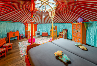 Colorful interior of a traditional Mongolian yurt called La Pause Insolite in Belgium, with wood furniture.
