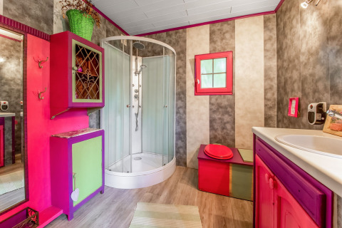 Colorful bathroom in a yurt at La Pause Insolite in Belgium featuring shower, quirky cabinets and decor.