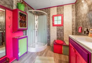 Colorful bathroom in a yurt at La Pause Insolite in Belgium featuring shower, quirky cabinets and decor.