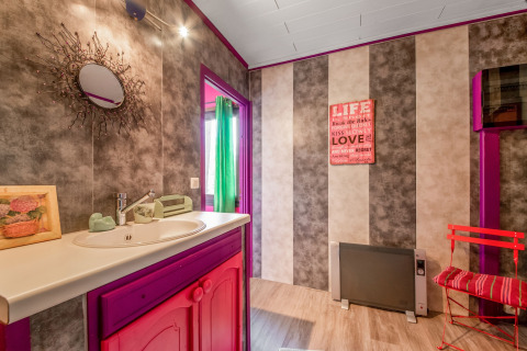 Colorful yurt bathroom in Belgium with pink and purple decor, mirror, striped walls, and quote art.