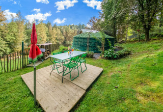 Outdoor dining area with green chairs by a yurt, surrounded by nature at La Pause Insolite in Belgium.