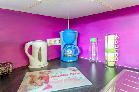 Colorful kitchen corner at La Pause Insolite yurt in Belgium featuring kettle, coffee maker, mugs, and decor.