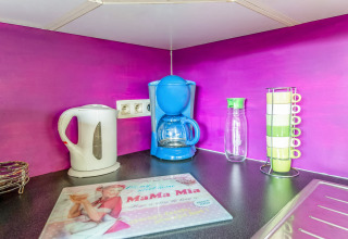 Colorful kitchen corner at La Pause Insolite yurt in Belgium featuring kettle, coffee maker, mugs, and decor.