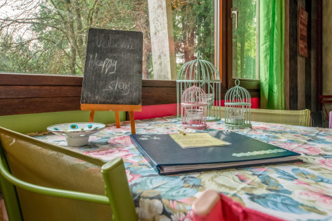 Cozy table setup inside yurt La Pause Insolite in Belgium, with birdcages, menu, and welcome board.